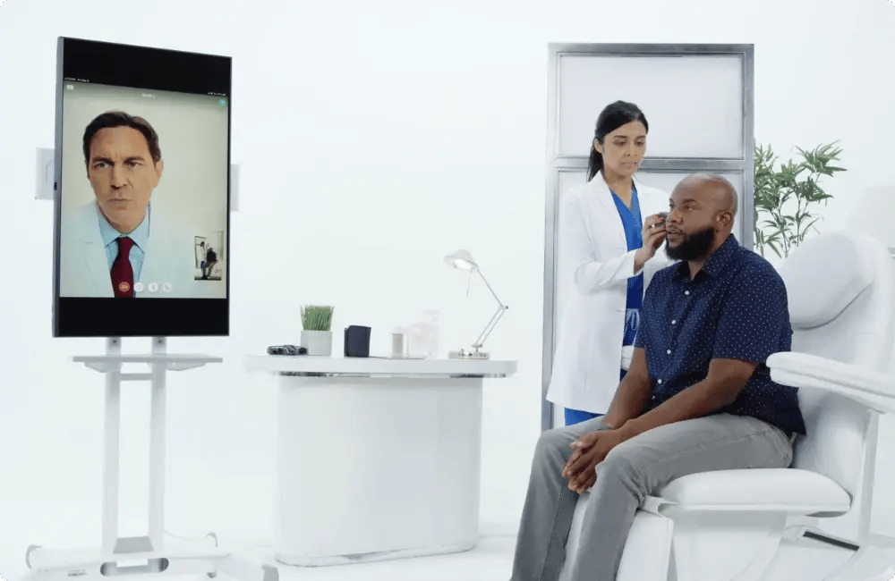 Patient and nurse joining a doctor by telehealth screen inside an on-site workplace clinic for InHouse Physicians.